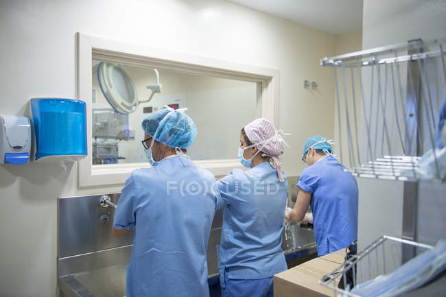 Rear view of doctors in uniform washing hands before operation — Stock Photo