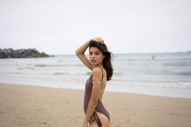 Vue latérale de la fille brune en maillot de bain posant sur la plage — Photo de stock