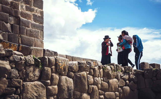 AYACUCHO, PERU - DEZEMBRO 30, 2016: Nativos de pé na parede de tijolos antigos — Fotografia de Stock