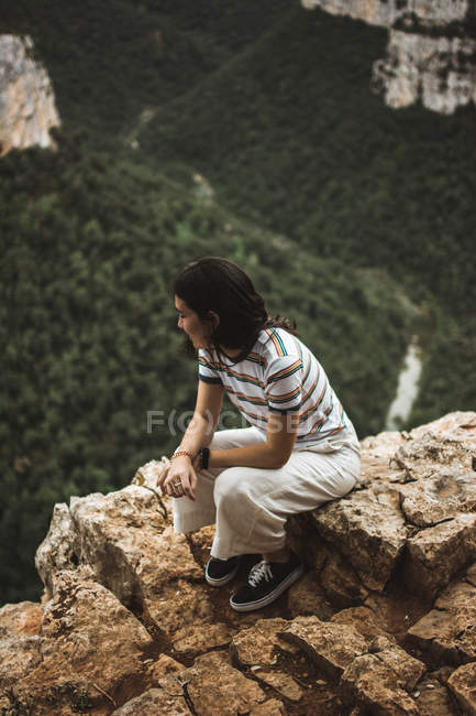 Брюнетка сидит на камне над лесом на заднем плане — стоковое фото