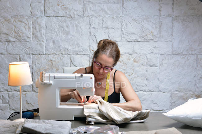 Thoughtful female tailor sitting and working in workshop. — Stock Photo