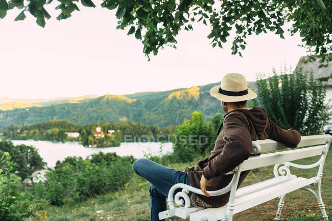 Hombre con sombrero sentado en el banco - foto de stock