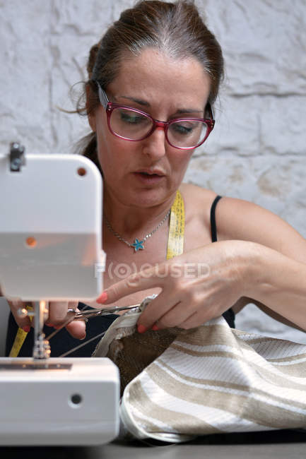 Frau sitzt und arbeitet an Nähmaschine. — Stockfoto