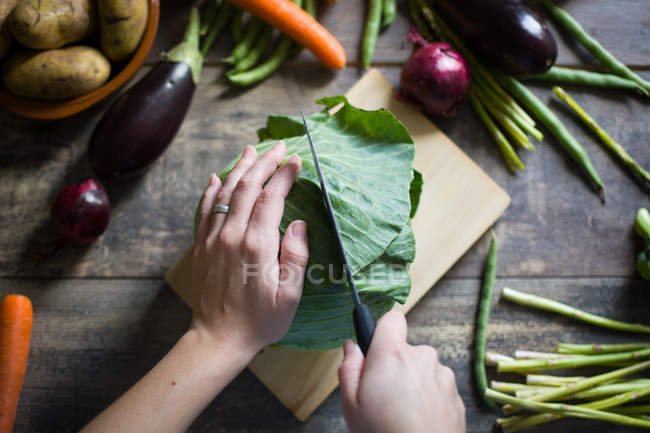 Женские руки режут свежую капусту на деревянной доске — стоковое фото
