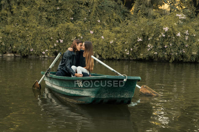 Sinnliches Paar umarmt sich auf Boot am See über Büsche im Hintergrund — Stockfoto