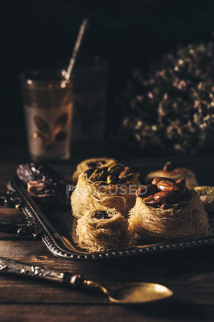 Delicioso postre sirio en plato con té en mesa de madera . - foto de stock