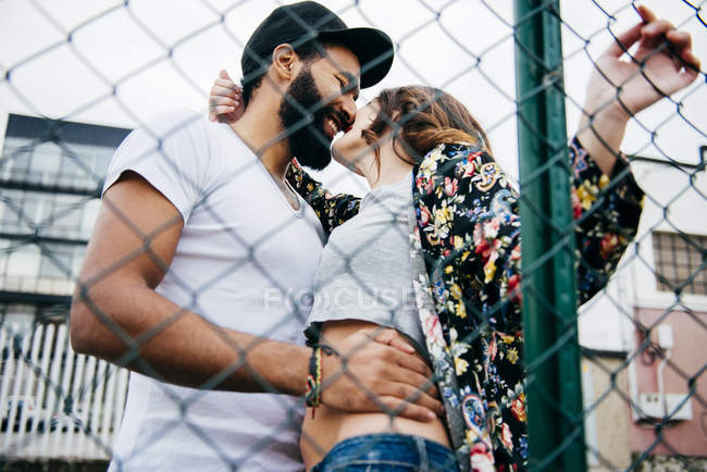 Couple posant derrière une clôture métallique — Photo de stock