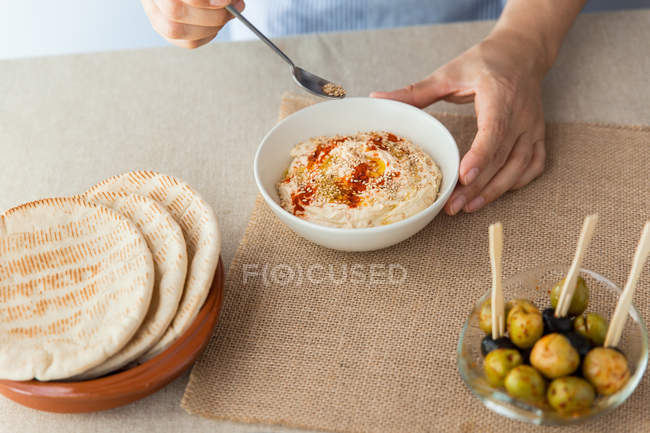 Frau dekoriert Hummus mit Sesam — Stockfoto