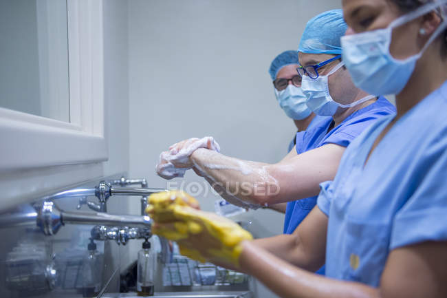 Seitenansicht von Chirurgen, die sich die Hände waschen und auf die Operation vorbereiten. — Stockfoto