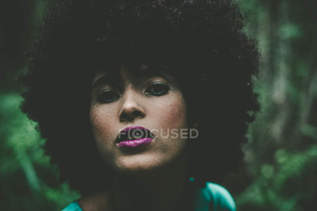 Portrait of sensual girl with afro haircut over greenery — Stock Photo