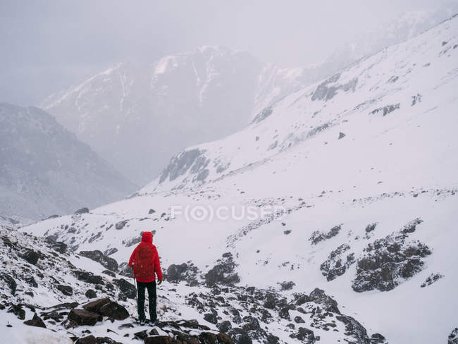 Unbekannter bewundert verschneite Berge an nebligem Tag — Stockfoto