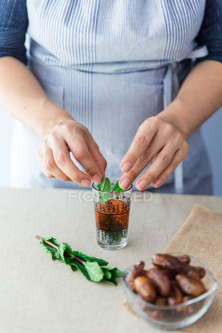 Cook putting leaves in glass — Stock Photo