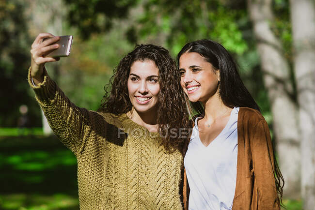 Due giovani belle amiche che fanno selfie nel parco. — Foto stock