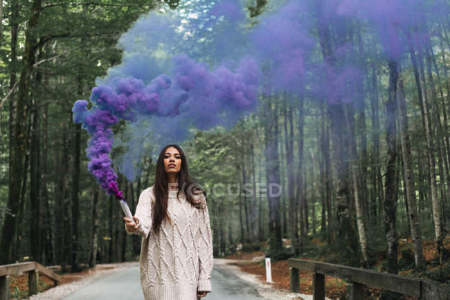 Женщина идет с фиолетовым дымовым факелом — стоковое фото