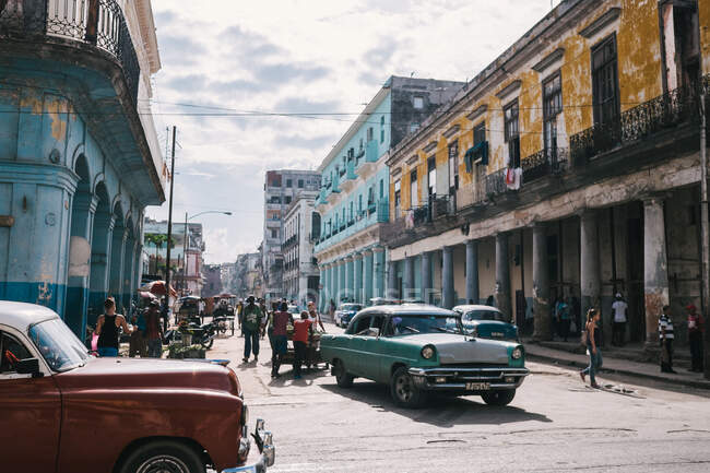 Foule de personnes et de vieilles voitures classiques dans la rue de la ville cubaine. — Photo de stock