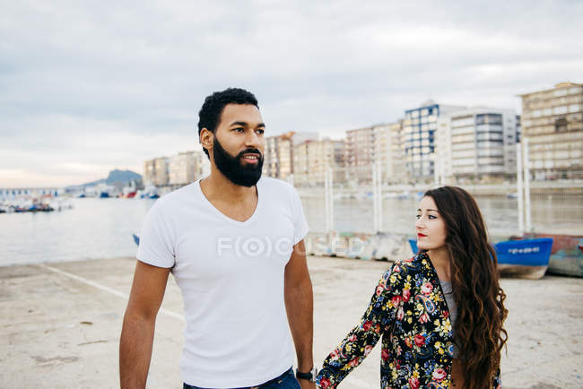 Couple holding hands and walking at coastal street — Stock Photo