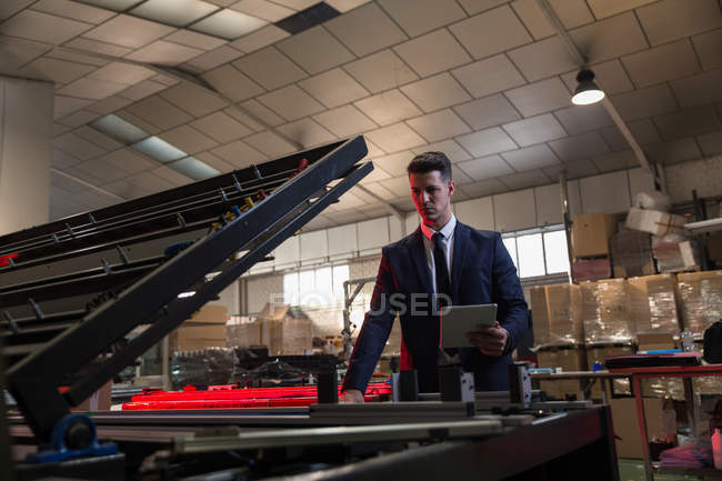 Formal man with tablet checking conditions on factory — Stock Photo