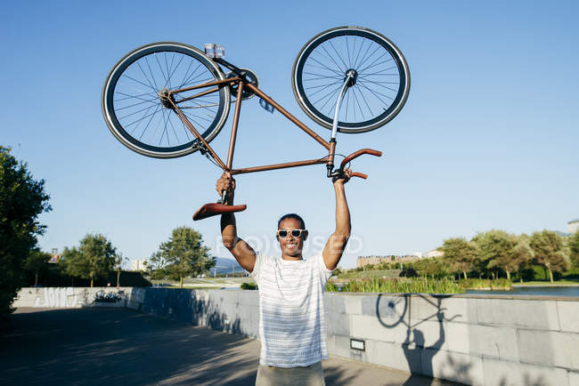 Uomo tenendo bicicletta sopra la testa — Foto stock