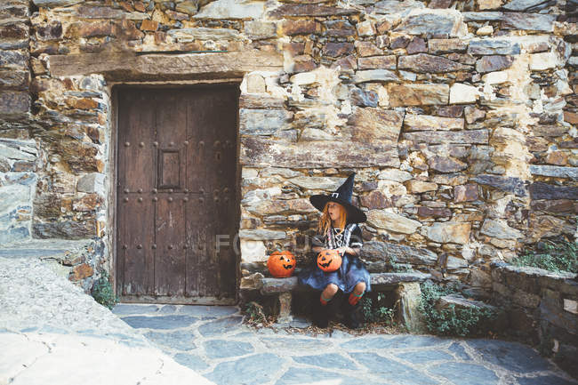 Дівчина в костюмі відьми сидить на лавці — стокове фото
