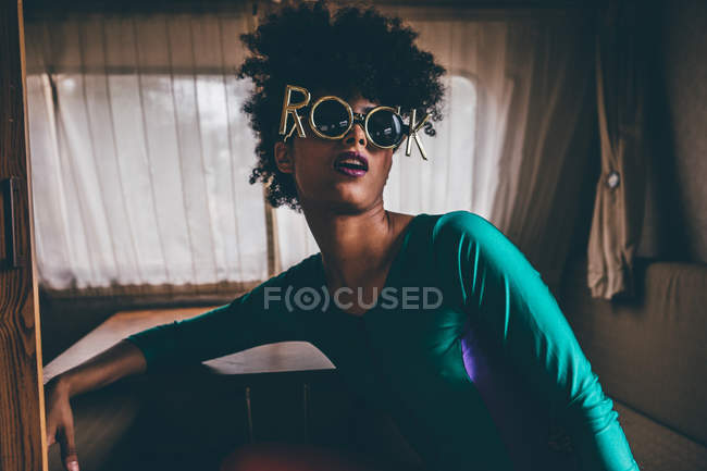 Young woman with afro wearing comical sunglasses inside of trailer — Stock Photo