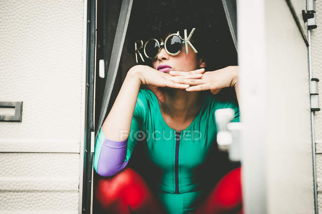 Ексцентрична жінка в комічних сонцезахисних окулярах сидить з перехрещеними пальцями — стокове фото
