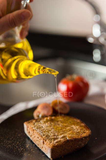 Pessoa derramando óleo sobre torrada — Fotografia de Stock
