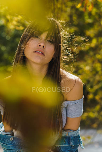 Вид сквозь осенние листья на красивую женщину, смотрящую в камеру — стоковое фото