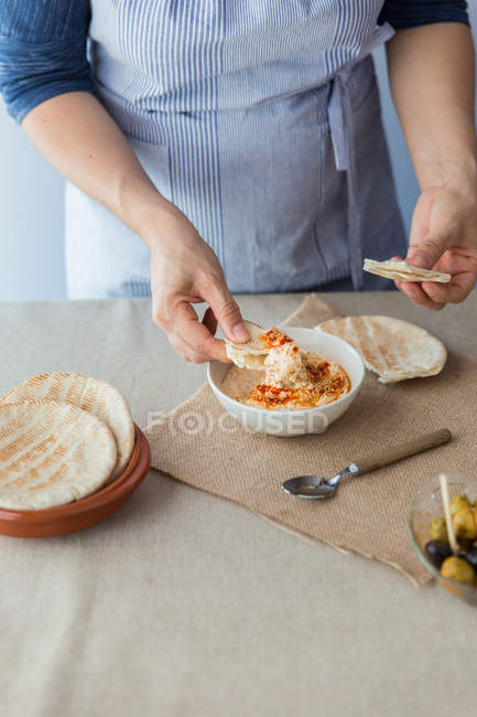 Woman dipping pita bread in hummus — Stock Photo