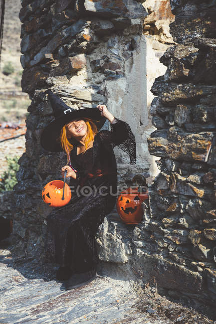 Mädchen mit Hexenhut posiert an Steinmauer — Stockfoto