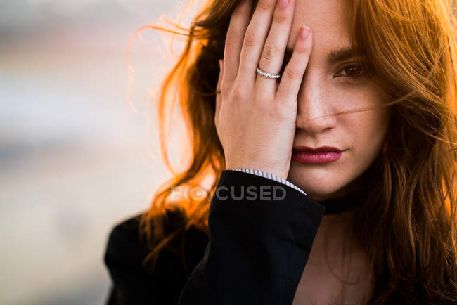 Porträt einer Frau, die ein Auge mit der Hand schließt und in die Kamera blickt. — Stockfoto
