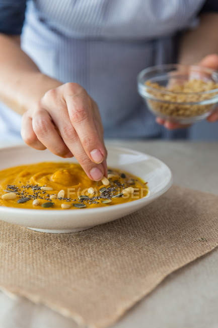 Cook decorating cream soup with seeds. — Stock Photo