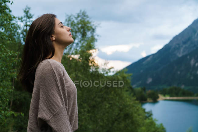 Morena chica posando sobre montaña lago - foto de stock