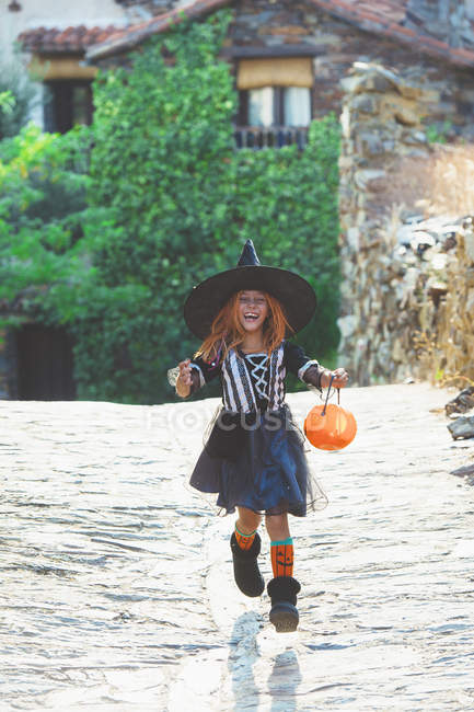 Girl with pumpkin basket running street — Stock Photo