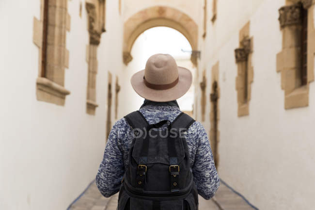 Vue arrière du touriste masculin avec sac à dos portant un chapeau et debout à la rue . — Photo de stock