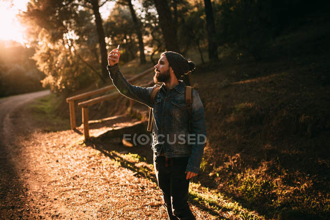 Homem tomando selfie na ensolarada estrada de outono — Fotografia de Stock