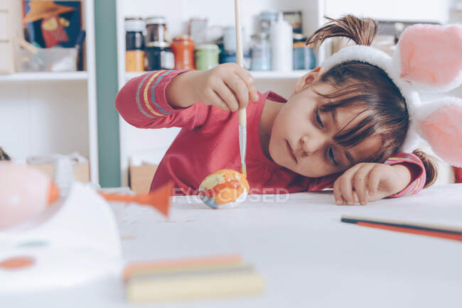Маленькая девочка рисует пасхальное яйцо — стоковое фото