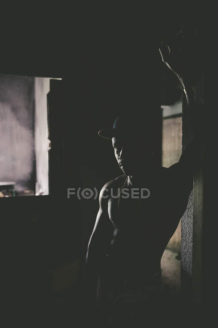 Ritratto di uomo muscoloso in posa in camera oscura e appoggiato alla parete
. — Foto stock
