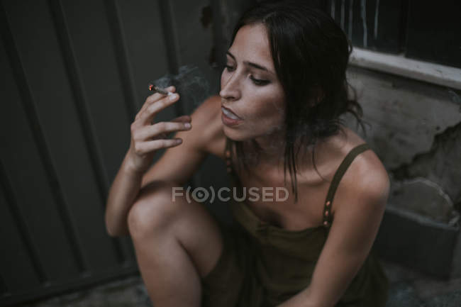 Portrait of brunette woman smoking cigarette and looking away pensively — Stock Photo