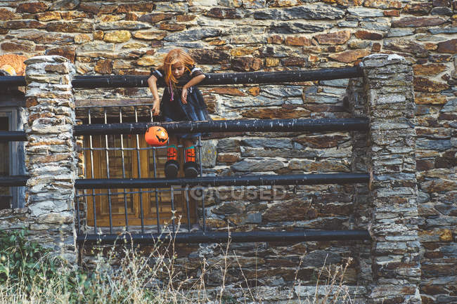 Chica con cesta de calabaza posando en la cerca - foto de stock