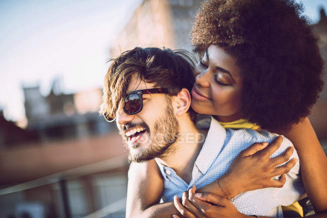 Retrato de pareja interracial abrazándose en la azotea - foto de stock