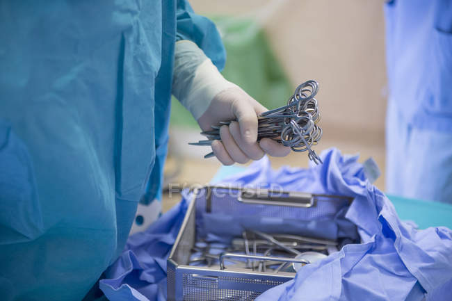 Mid section view of doctors hand taking surgery equipment from table — Stock Photo