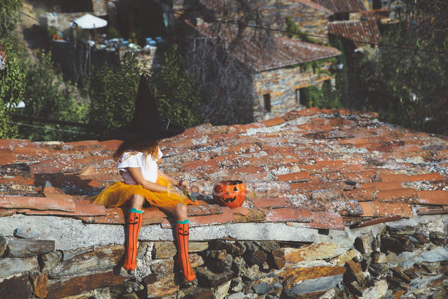 Fille en costume d'Halloween assis sur le toit — Photo de stock
