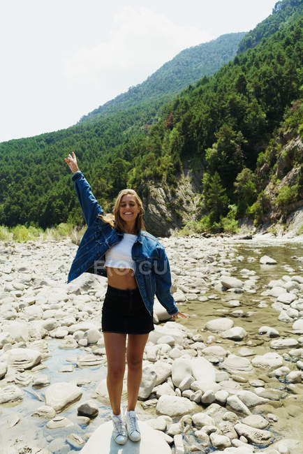 Glückliches Mädchen posiert auf den Steinen eines Flusses — Stockfoto