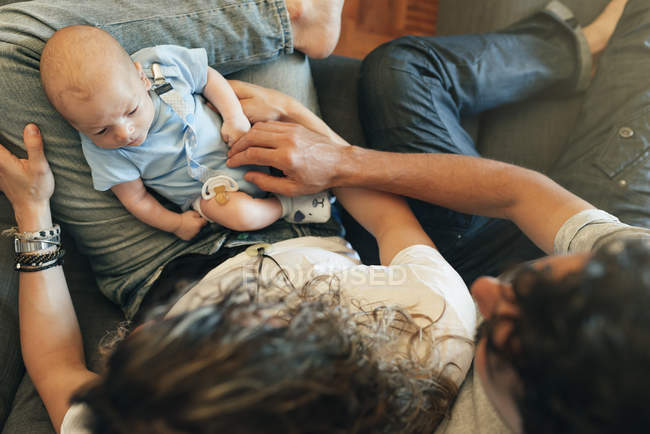 Happy young couple with newborn baby on knees — Stock Photo