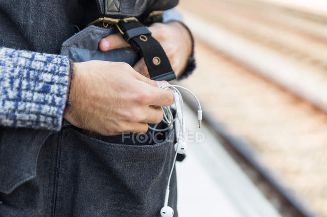 Crop image of male hands taking earphones from bag. — Stock Photo