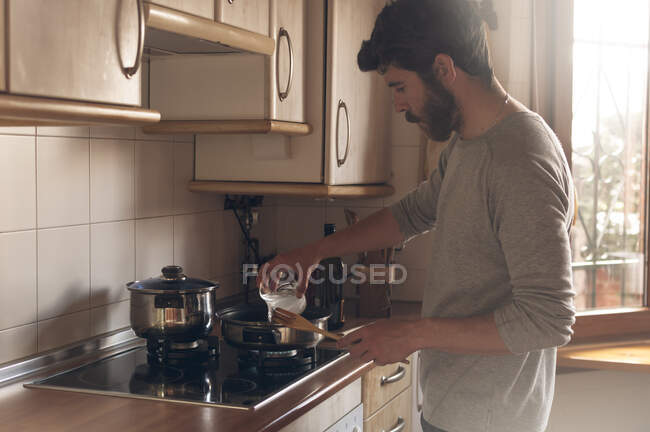 Ordinary man cooking bathed in the soft light coming through the window — Stock Photo