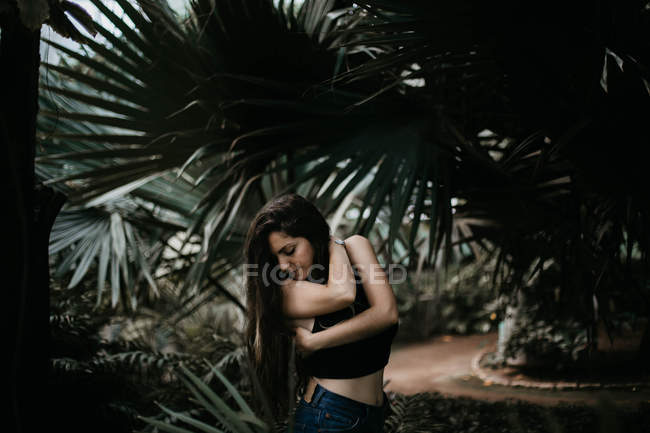 Morena chica posando sobre hojas de palma - foto de stock