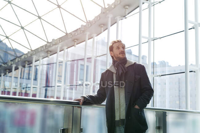 Young man at the station illuminated by the sunlight through the glass windo — Stock Photo