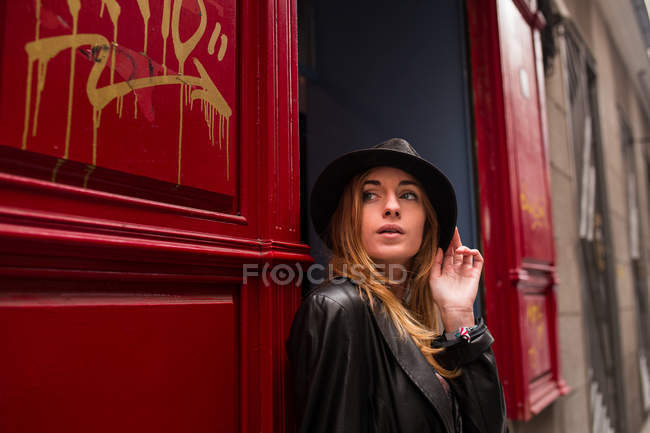 Young girl in hat looking away while standing in doorway — Stock Photo