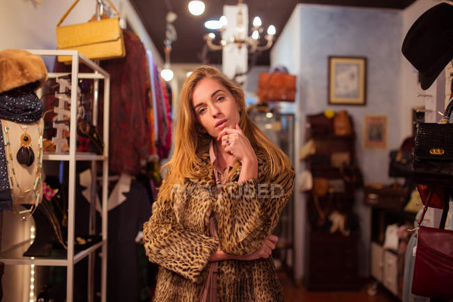 Junges Mädchen posiert im Pelzmantel in der Kleiderkammer und blickt in die Kamera — Stockfoto